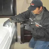 Bed bug inspection technician checking a mattress and bed frame for signs of infestation in Spokane, WA