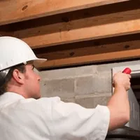Termite inspection technician checking a basement wall and framing for termite activity in Spokane, WA